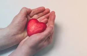 man holding red heart in his hands